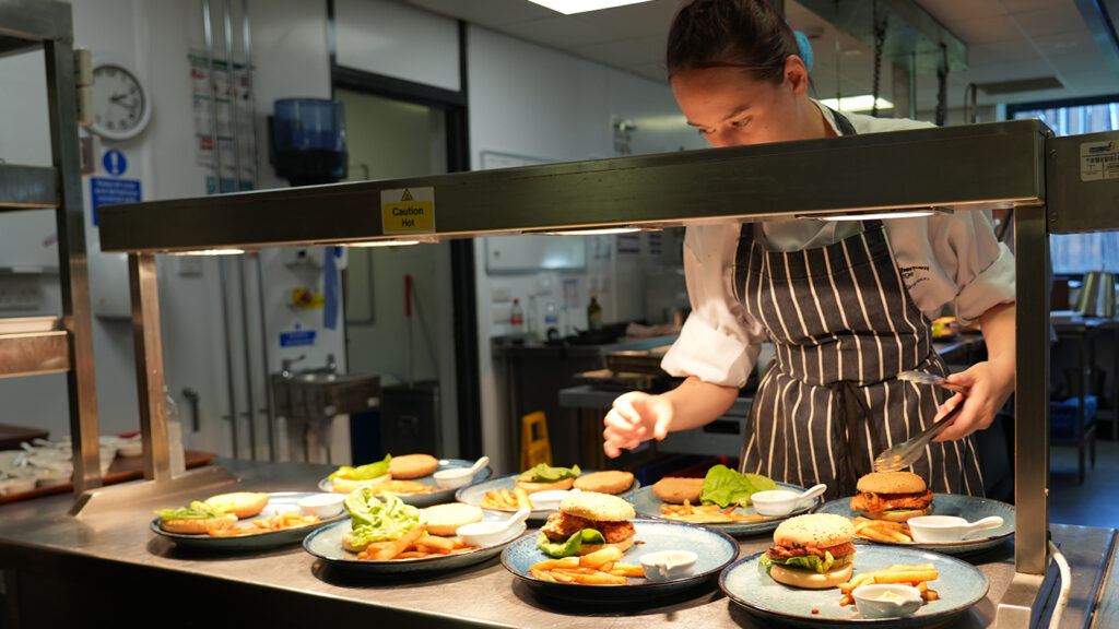 A chef preparing several plates of food in the kitchen