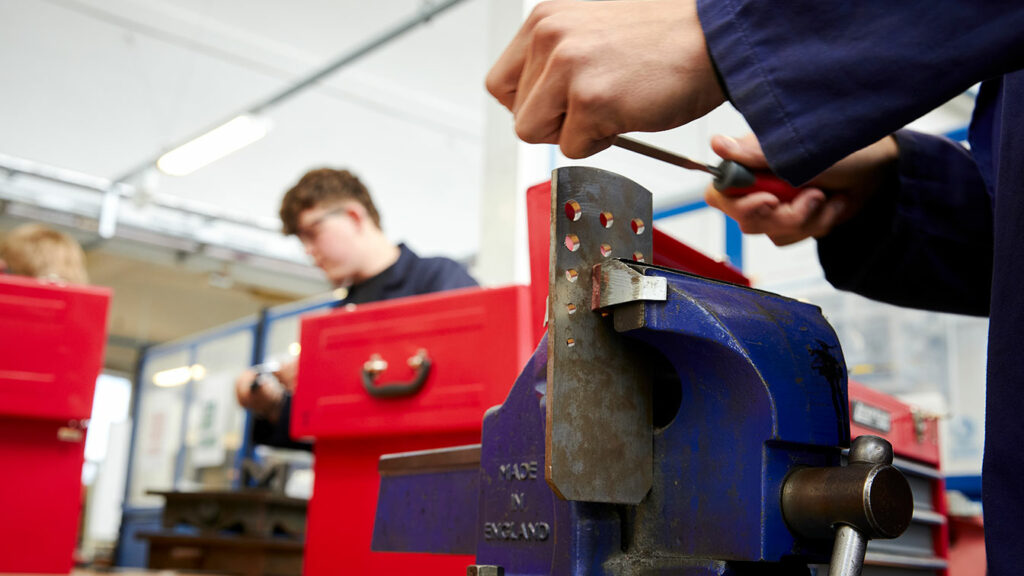 A close up of a student using a vice in the engineering workshop