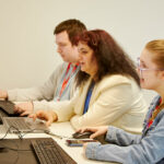 Three students sat working at laptops