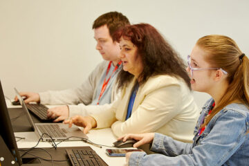 Three students sat working at laptops