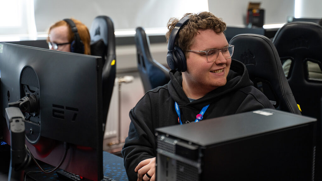 Someone wearing headphones sat in front of a computer turning their head to the left