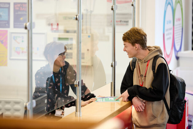 A student talking to a member of staff at the reception