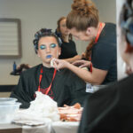 A media make-up student putting make up on someone's face