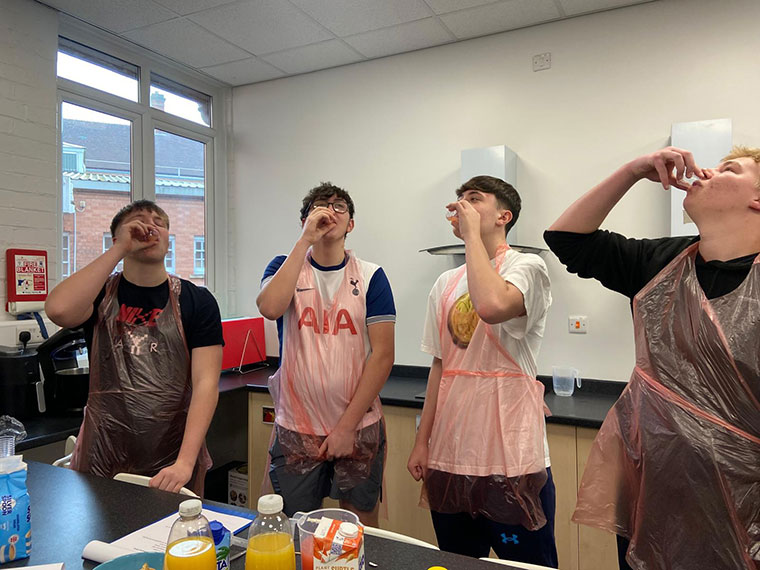 Students stood around a table drinking from cups