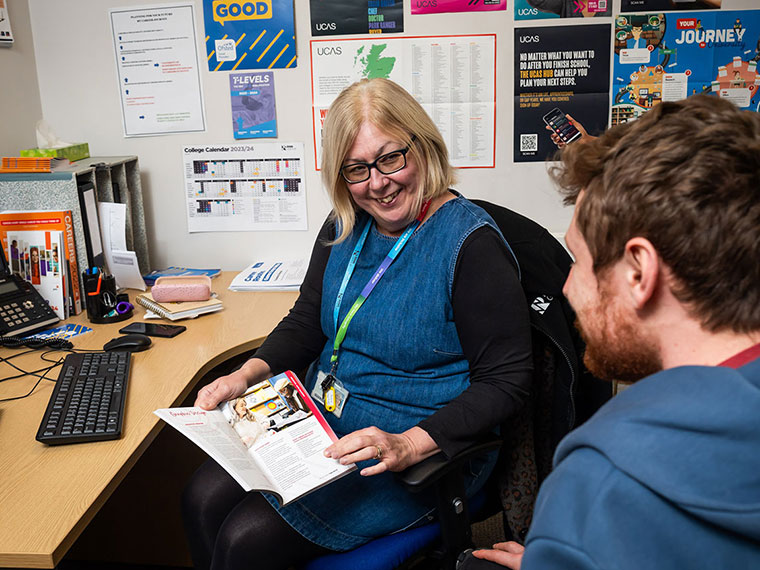 A member of staff sat at a desk speaking to someone