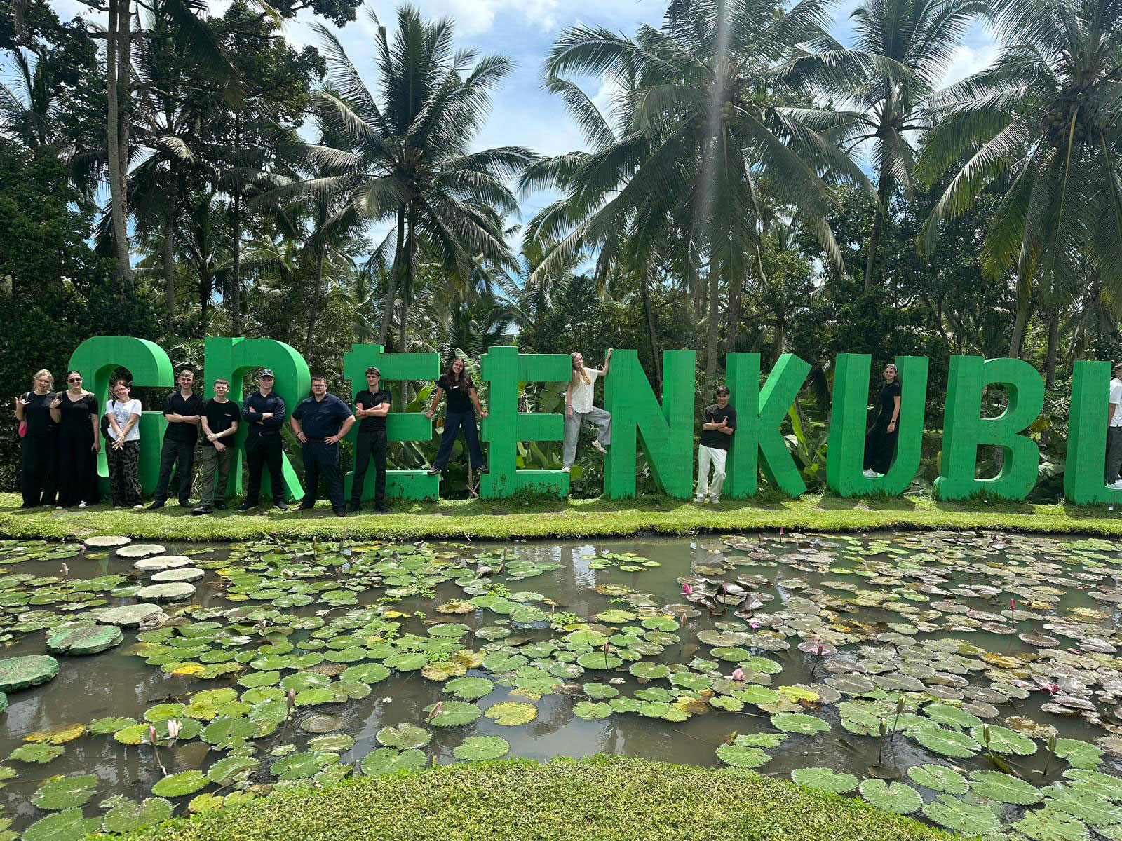 A group of people stood in front of large green letters