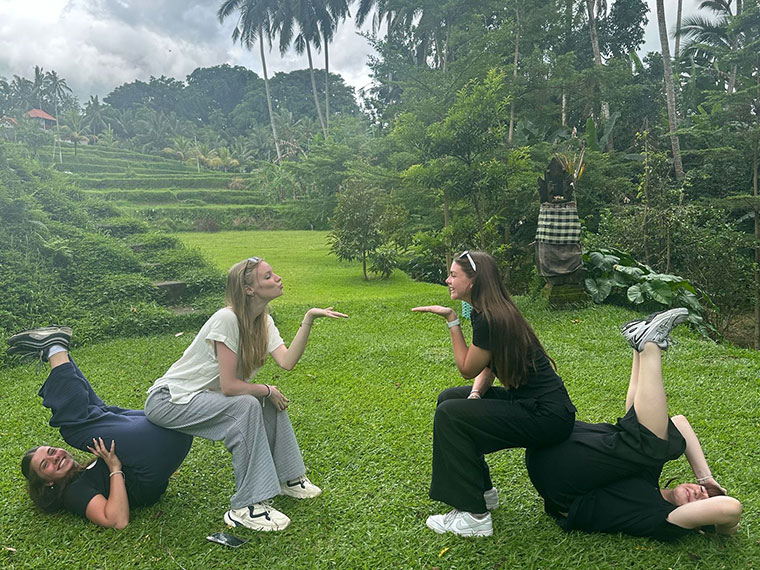 Four students posing in different shapes on grass