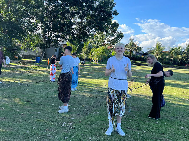Students taking part in Indonesian games on grass under blue skies