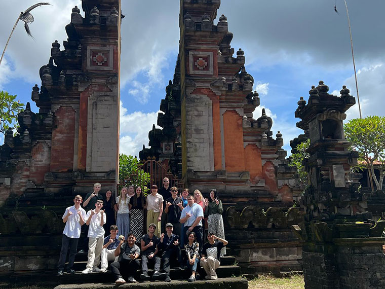 A group of people sat and stood on steps in front of a monument in Bali