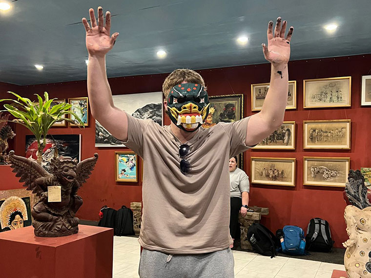 A person wearing a mask that they have made, their hands raised in the air