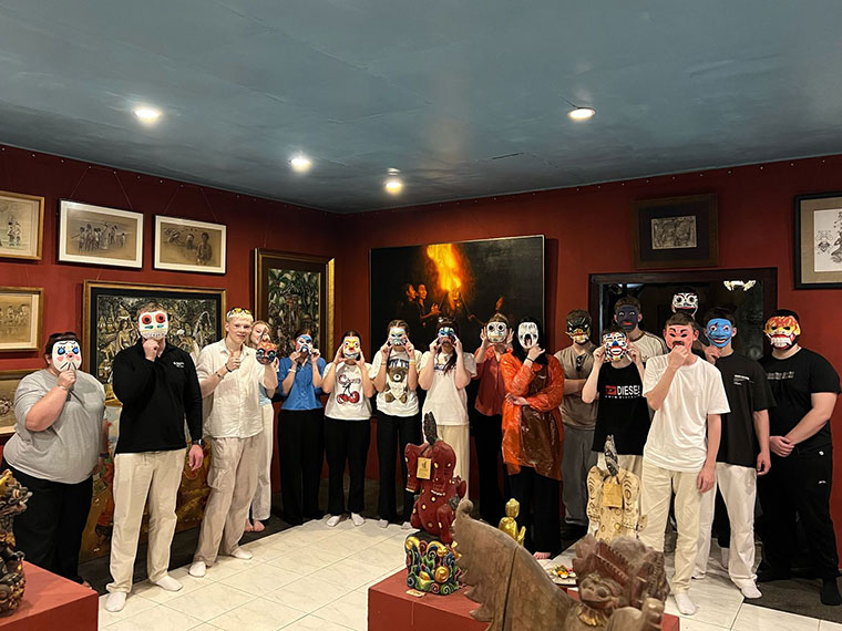 A group of students holding mask that they have made up to their faces