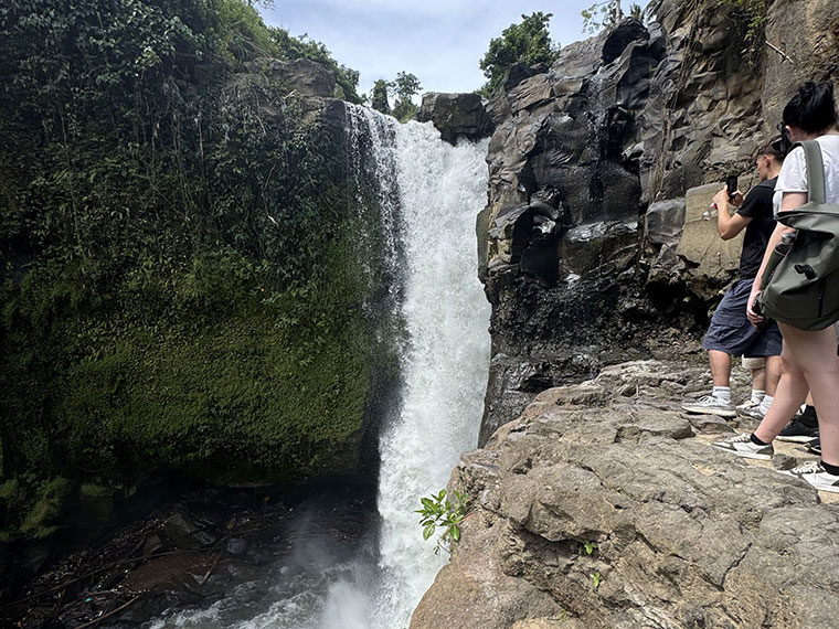 People taking a photo of a stunning waterfall in Bali