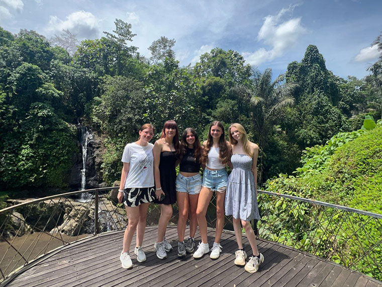 Five student stood together with the Tegenungan Waterfall, Bali in the background