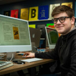 A graphic design student sat in front of an Apple Mac