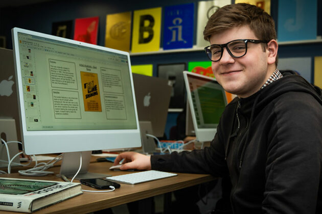 A graphic design student sat in front of an Apple Mac