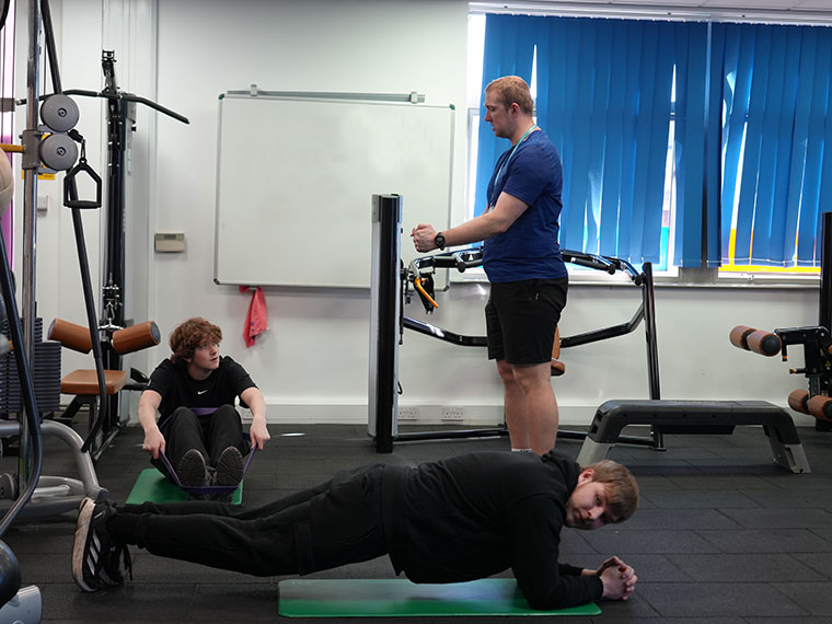 A gym instructor showing a student how to use some equipment