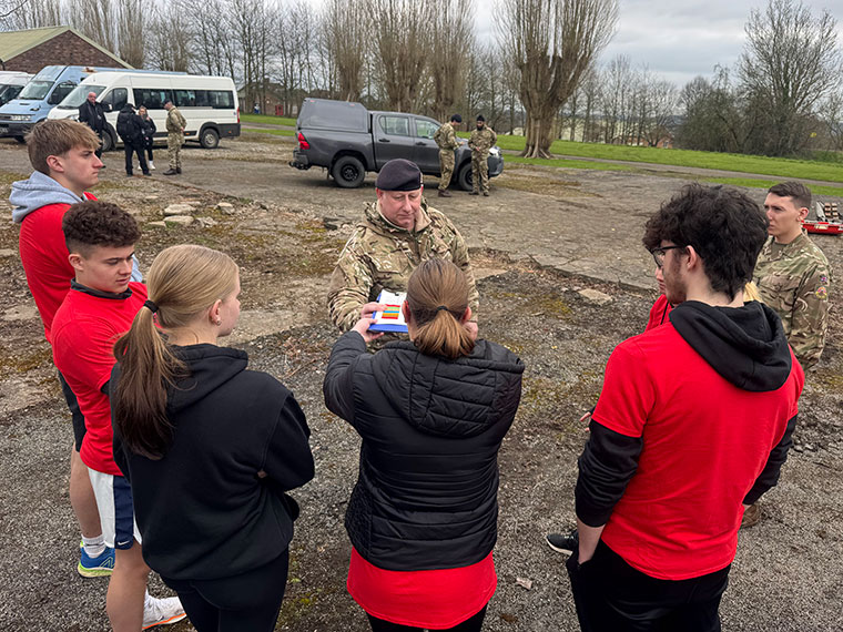 Students stood with a person wearing army clothing