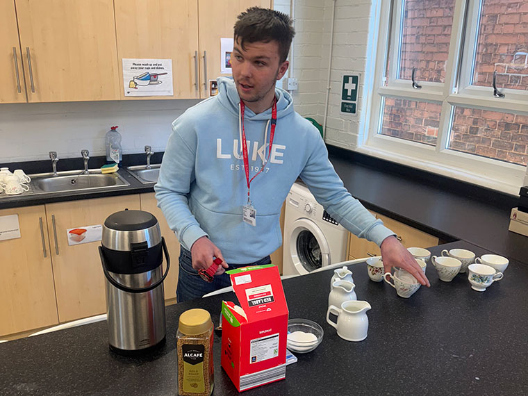 A student stood at a kitchen counter making cups of tea