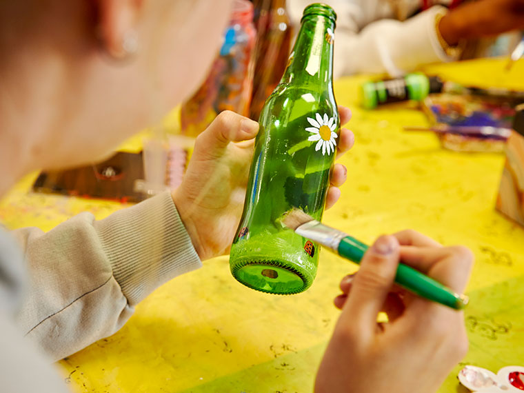 Someone holding a bottle and painting flowers on it