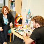 A member of staff sat at a table with a student