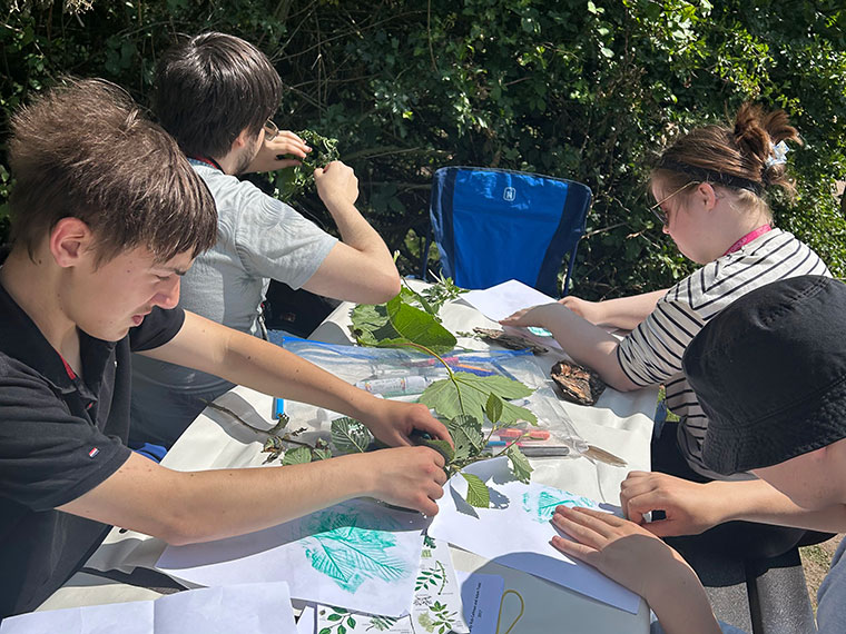 Students sat at a table outside being creative