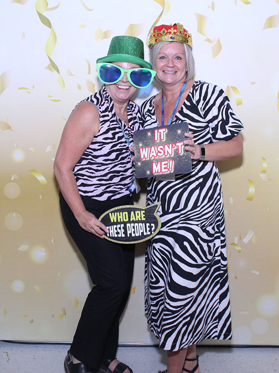 Two members of staff in the photo booth at the student celebration event 2024