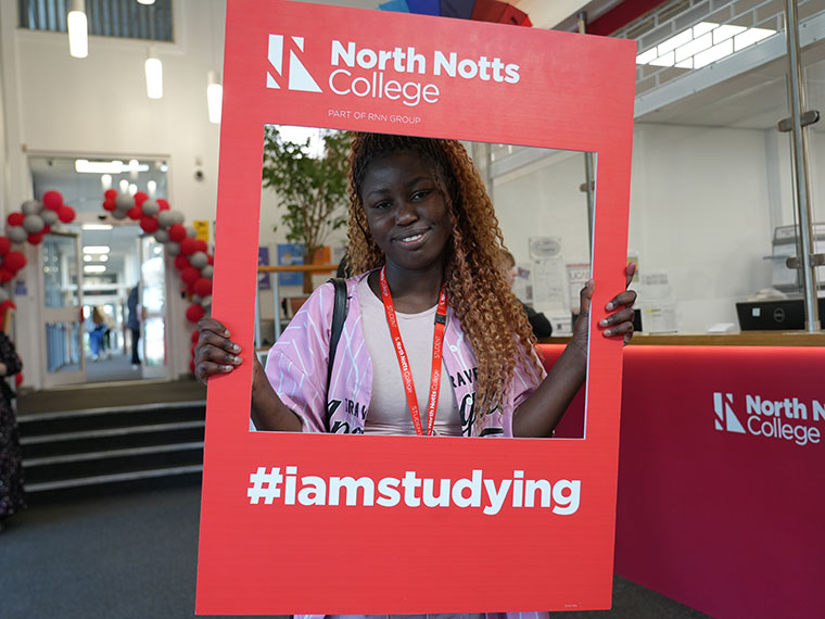 A smiling student holding a frame during welcome week 2025