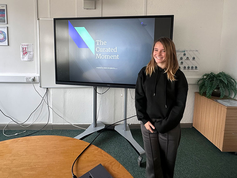 A student stood next to a large TV screen