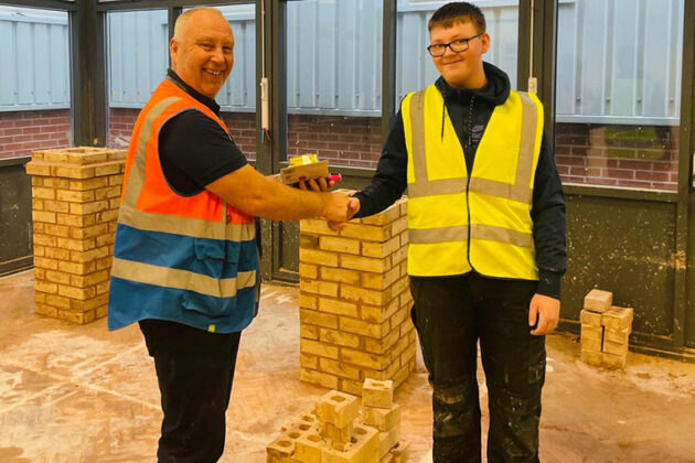 A construction student being presented with tools that he won in a challenge