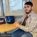 A student sat at a desk in front of a laptop and tablet