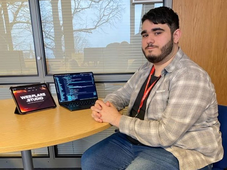 A student sat at a desk in front of a laptop and tablet