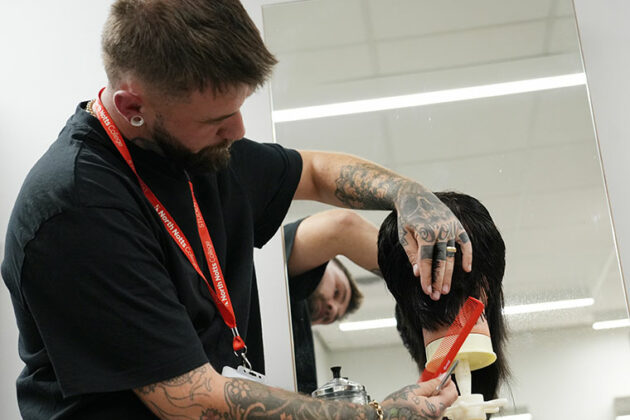 An adult learner cutting hair in the College's training salon