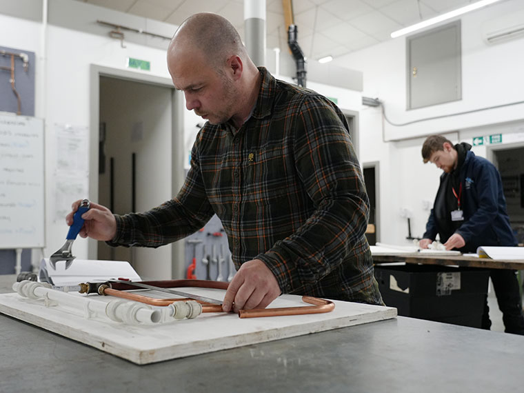 A student stood working on a plumbing project