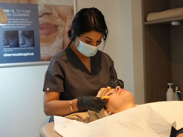 An adult learner giving a client an aesthetics treatment in the salon