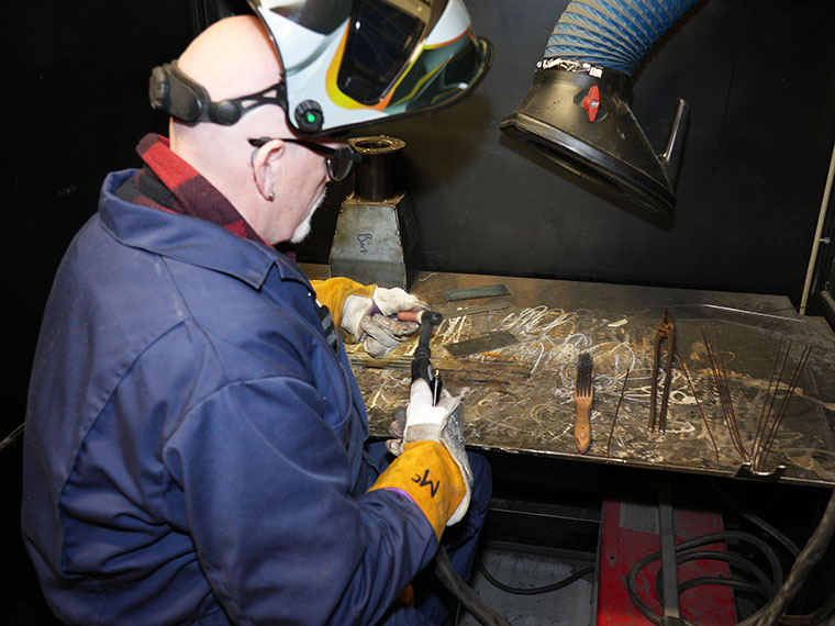An engineering adult learner with a protective mask on their head