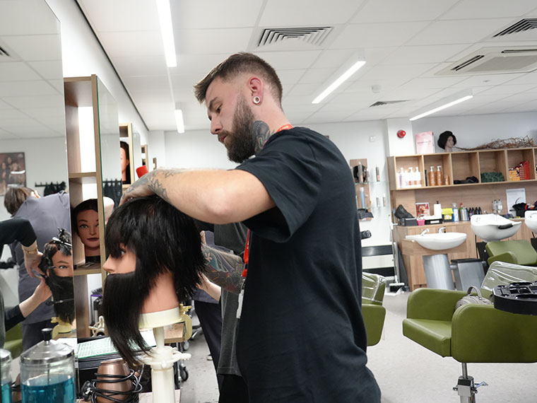 An adult hairdressing learner cutting hair in the salon