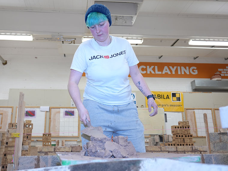 Adult bricklaying student Leah mixing cement