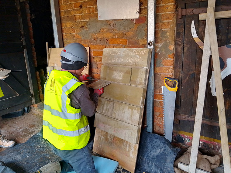 A student wearing a high vis jacket working on a plastering project