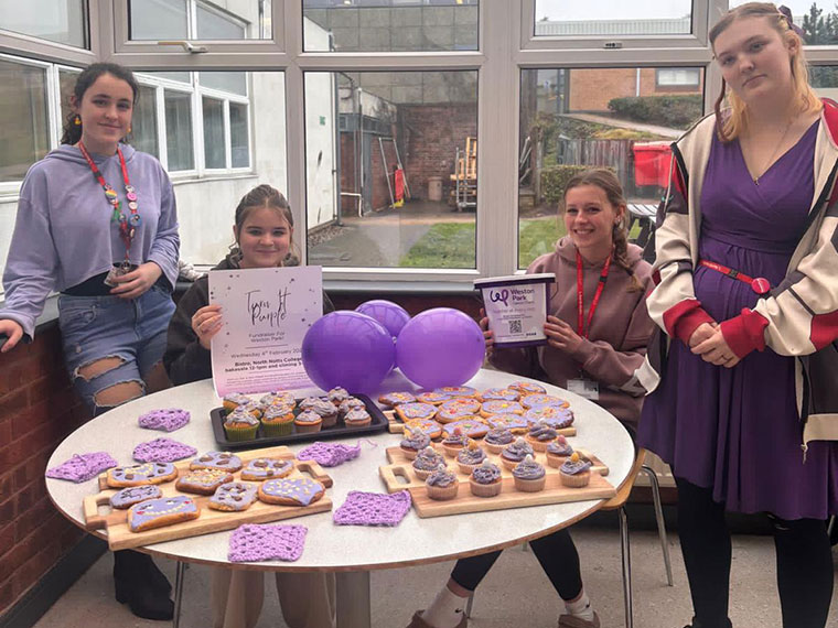 Students sat around a table of baked goods raising money on World Cancer Day