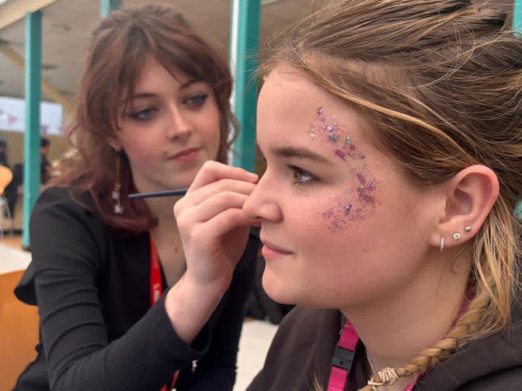 A student painting another students face