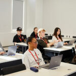 Students sat at desks in a classroom, all looking to the front