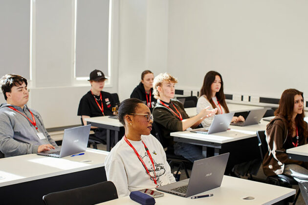 Students sat at desks in a classroom, all looking to the front
