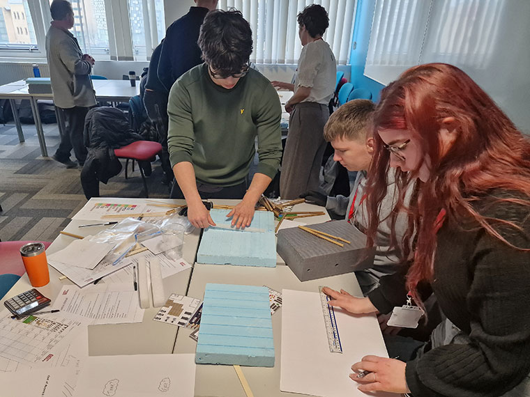 A group of students leaning over a table looking at items on there