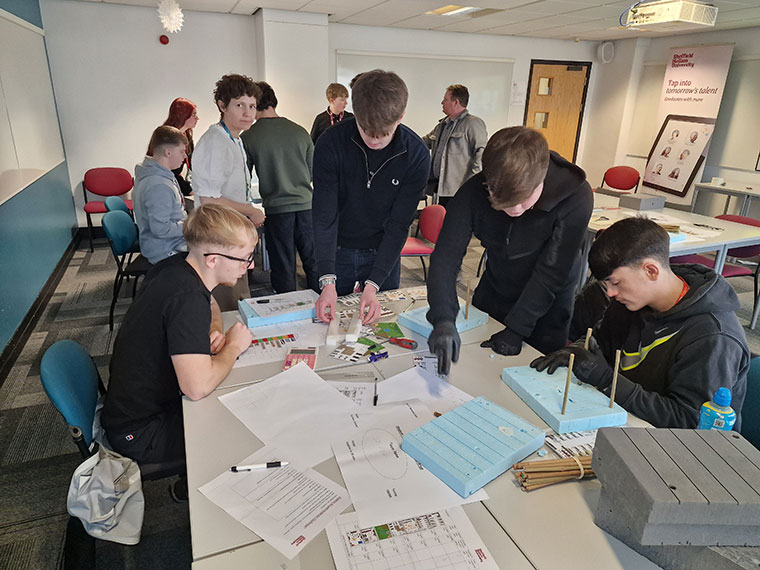 A group of students leaning over a table looking at items on there