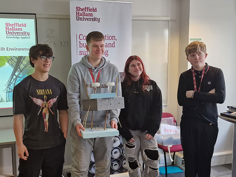 Four students stood together holding up a model