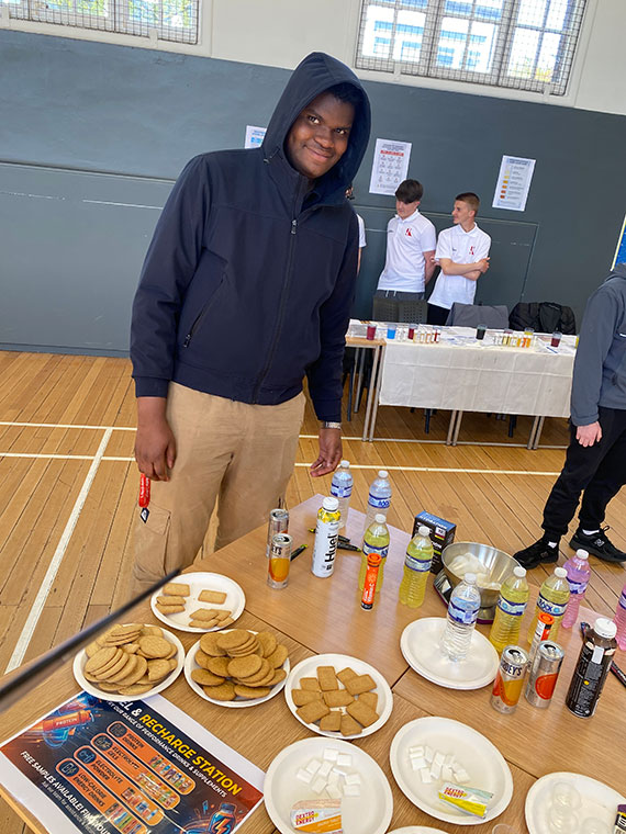 Someone stood at a table with lots of different sports drinks and food on there