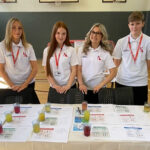 Four people stood behind a table with lots of different sports drinks on there
