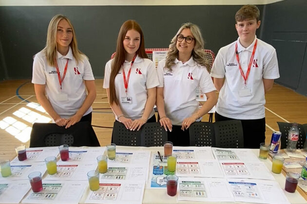 Four people stood behind a table with lots of different sports drinks on there