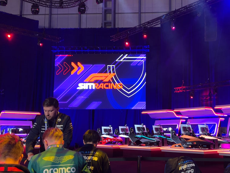 A large screen with three people in the foreground