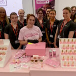 A group of students stood with a lady demonstrating Glitterbels products